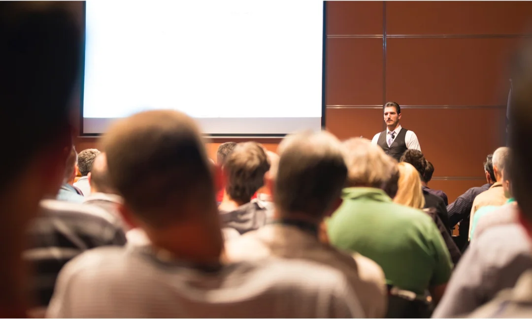 Business speaker presenting to an audience in a conference room.