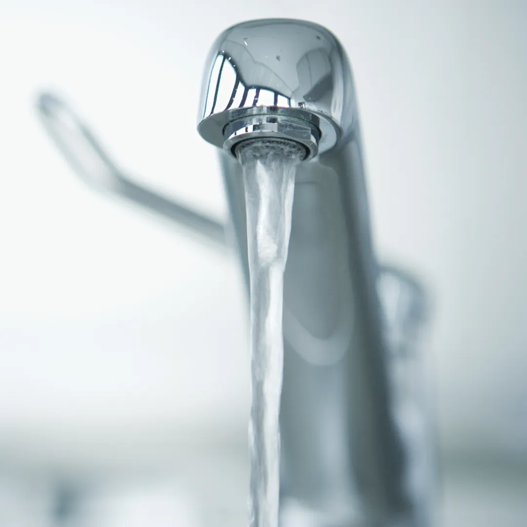 Clear water running from a chrome mixer tap.